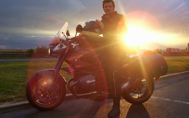 Motorradfahrer bei Sonnenuntergang auf Landstraße