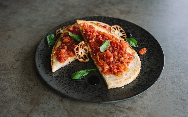 Bruschetta con pomodori e basilico su piatto nero