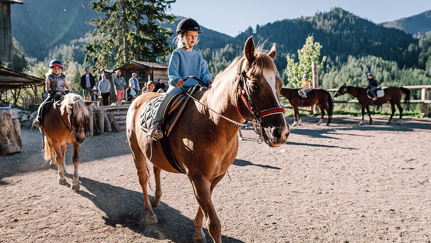 Children riding horses at a mountain riding arena