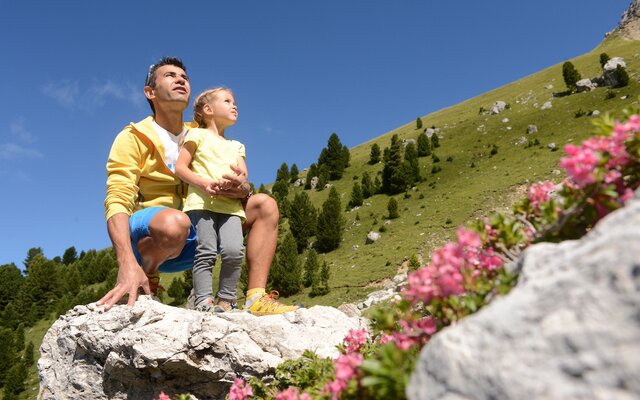 Padre e figlia seduti su una roccia in montagna