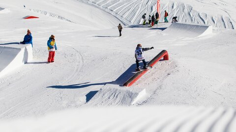 Snowboarding scene with an athlete performing a trick on a rail.