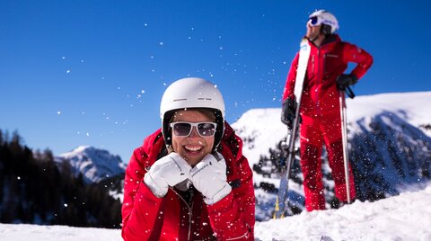 Ski scene with a person smiling in the snow.