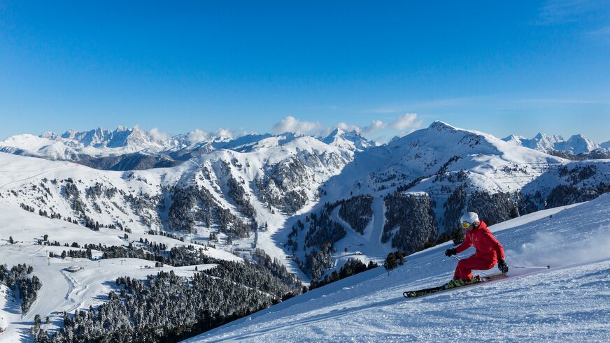 Skifahrer auf der Piste vor Bergpanorama