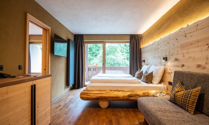Letto con testata in legno, divano e finestra panoramica.
